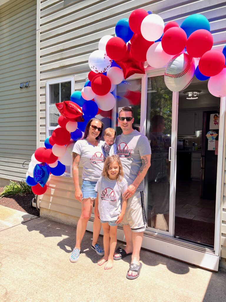 Family under baseball themed balloon arch