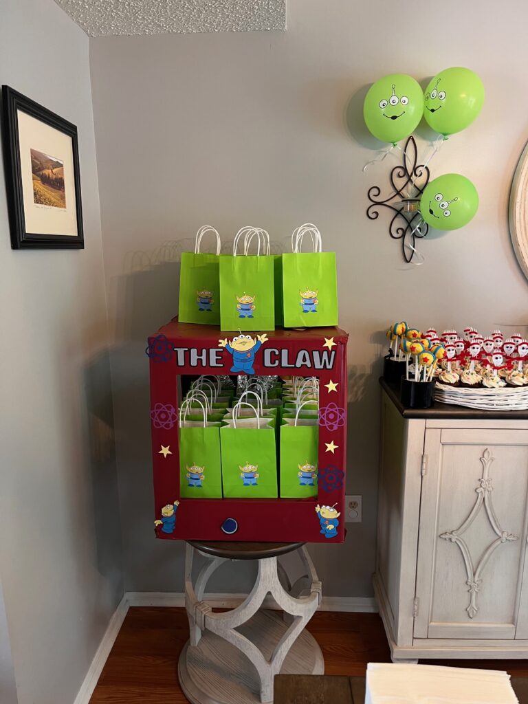 Claw machine party decoration with alien balloons and favor bags