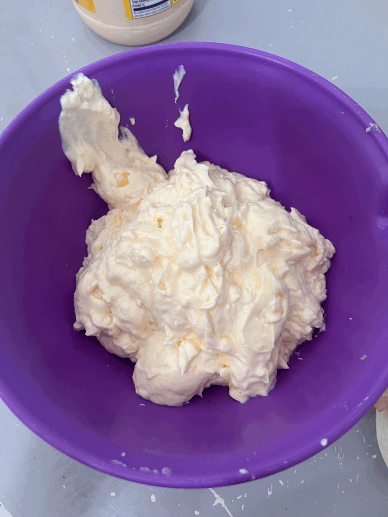 Creamy mayonnaise mixture in a purple bowl, ready to be folded into Nan’s homemade potato salad