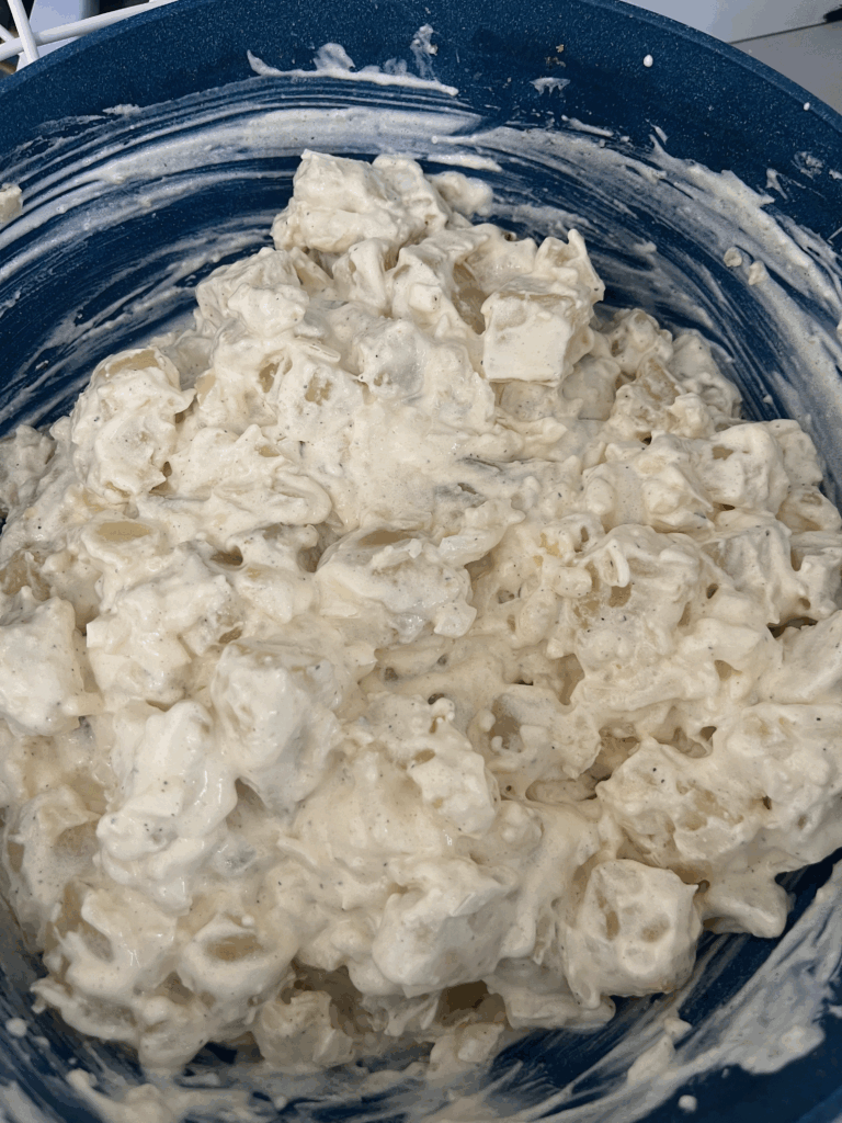 Fully mixed creamy potato salad in a blue bowl, made with mayonnaise, onions, and seasonings from a passed-down family recipe