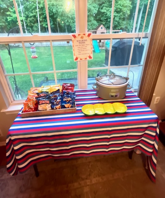 Walking taco bar setup with chip bags, slow cooker of taco meat, and serving plates for a carnival-themed birthday party”