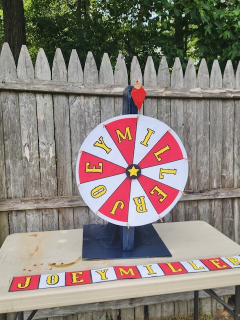 DIY carnival prize wheel made from cardboard, foam core, and cardstock for a backyard birthday party game