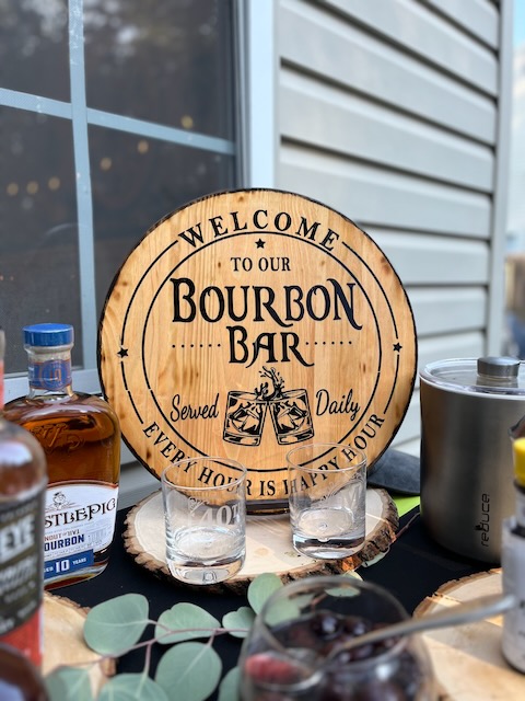 Custom wooden bourbon bar sign displayed at a Bourbon & BBQ 40th birthday party, surrounded by bourbon bottles and glassware.