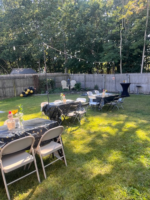 Backyard party setup with tables and chairs, and classic bourbon bottles as centerpieces 