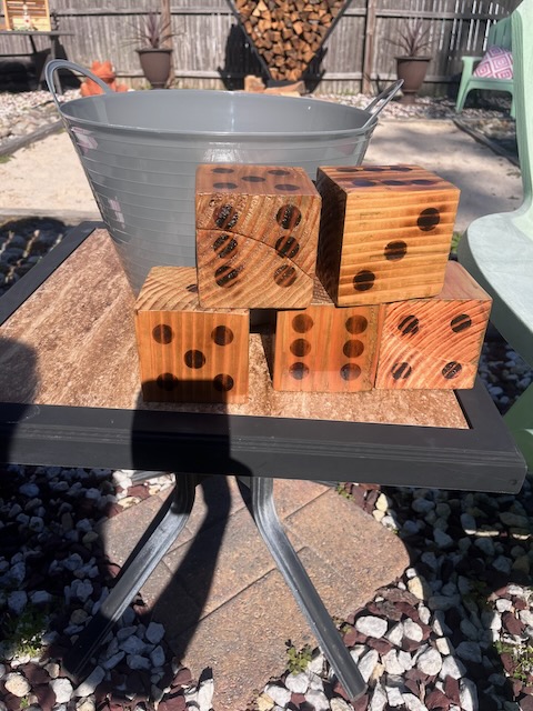 Set of oversized wooden dice stacked on a patio table for a DIY Yard Yahtzee game, part of the outdoor activities at a 40th birthday Bourbon and BBQ party.