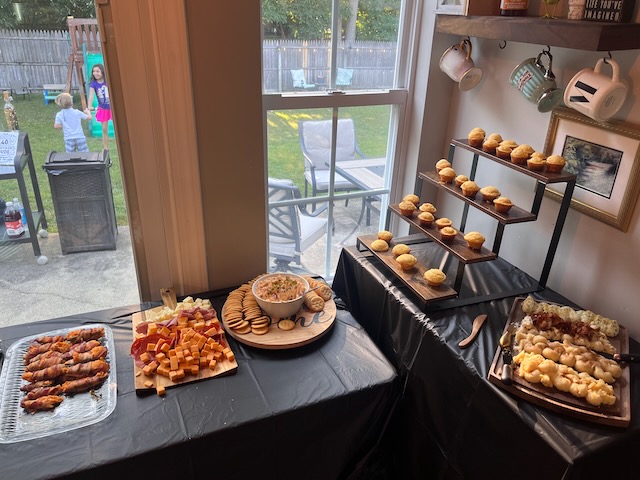 Appetizer grazing table at a Bourbon & BBQ 40th birthday party with bacon-wrapped jalapeños, cheese cubes, pimento cheese dip with crackers, mini cornbread muffins, and a butter board.