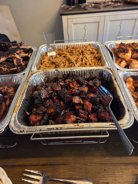 Buffet trays of BBQ pork belly burnt ends and shredded pulled pork at a Bourbon & BBQ 40th birthday party, served alongside chicken and ribs.
