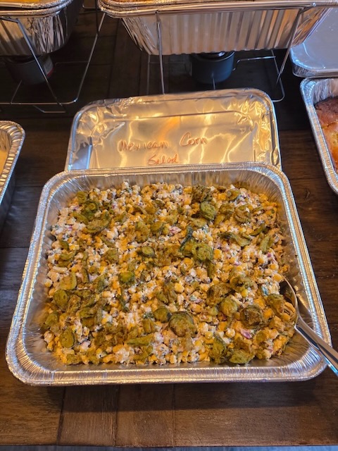 Pan of Mexican corn salad topped with jalapeño slices, served buffet-style at a Bourbon & BBQ 40th birthday party.