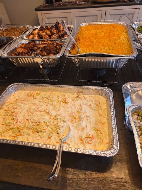 Catering trays of creamy coleslaw and baked mac and cheese served buffet-style at a Bourbon & BBQ 40th birthday party, alongside BBQ chicken.