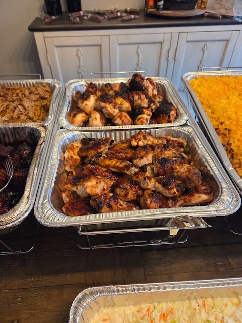 Buffet trays of BBQ chicken wings and legs served at a Bourbon & BBQ 40th birthday party, alongside pulled pork, pork belly, and mac and cheese.