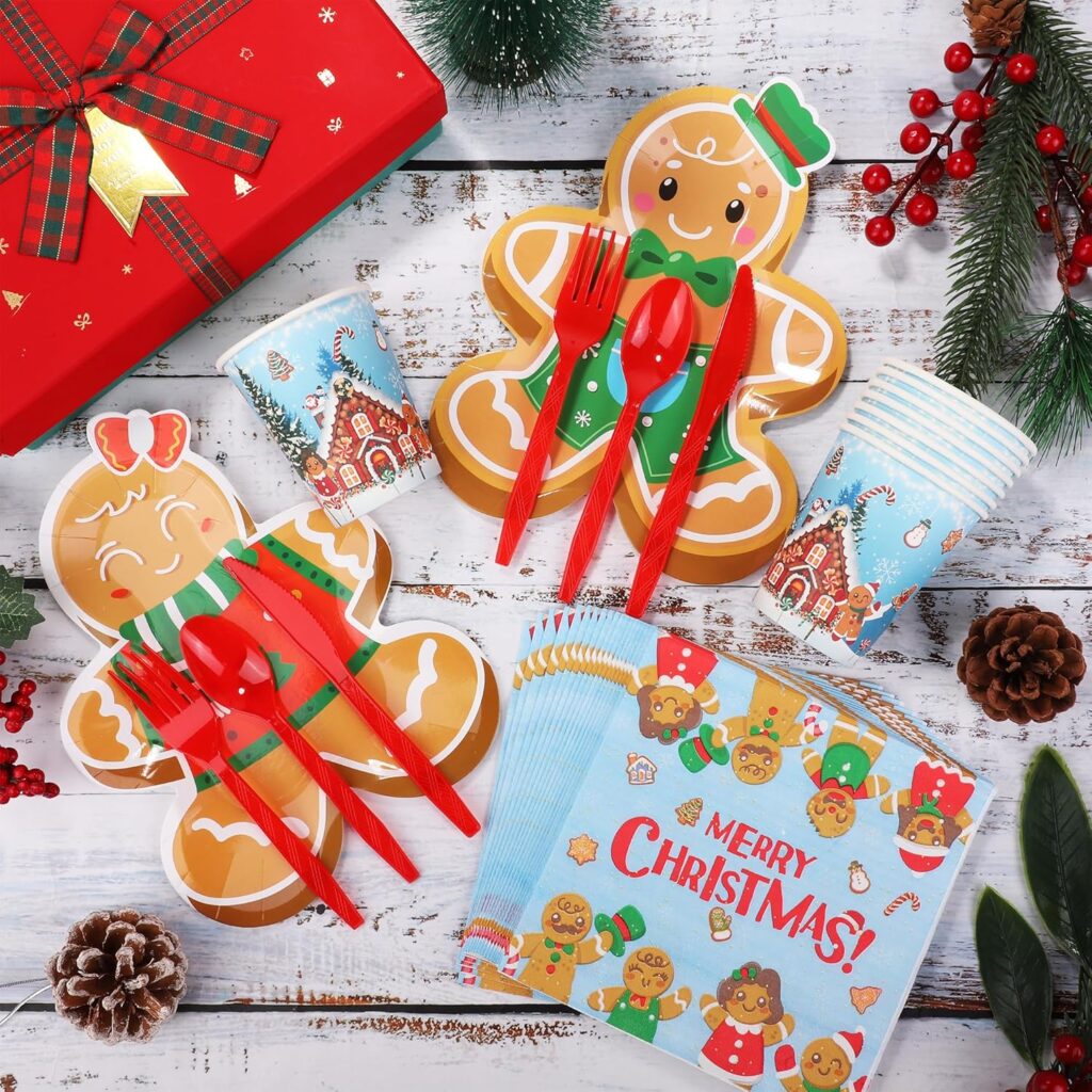 Gingerbread man Christmas party plates, cups, and napkins with red utensils and festive holiday gift box on a rustic white wood table.