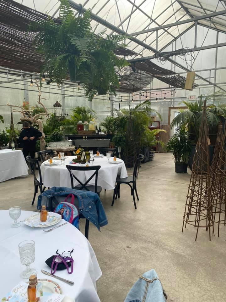 Greenhouse venue decorated for a vintage Winnie the Pooh baby sprinkle with garden party tables and lush greenery