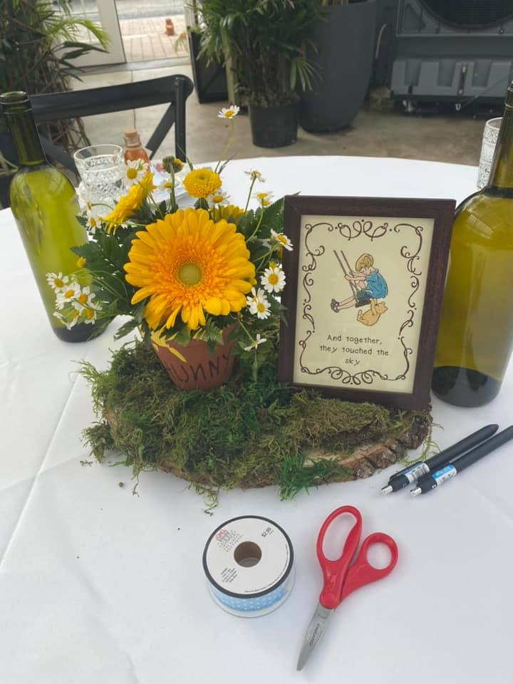 Winnie the Pooh baby sprinkle ribbon game table with rustic centerpiece, moss decor, and vintage storybook artwork