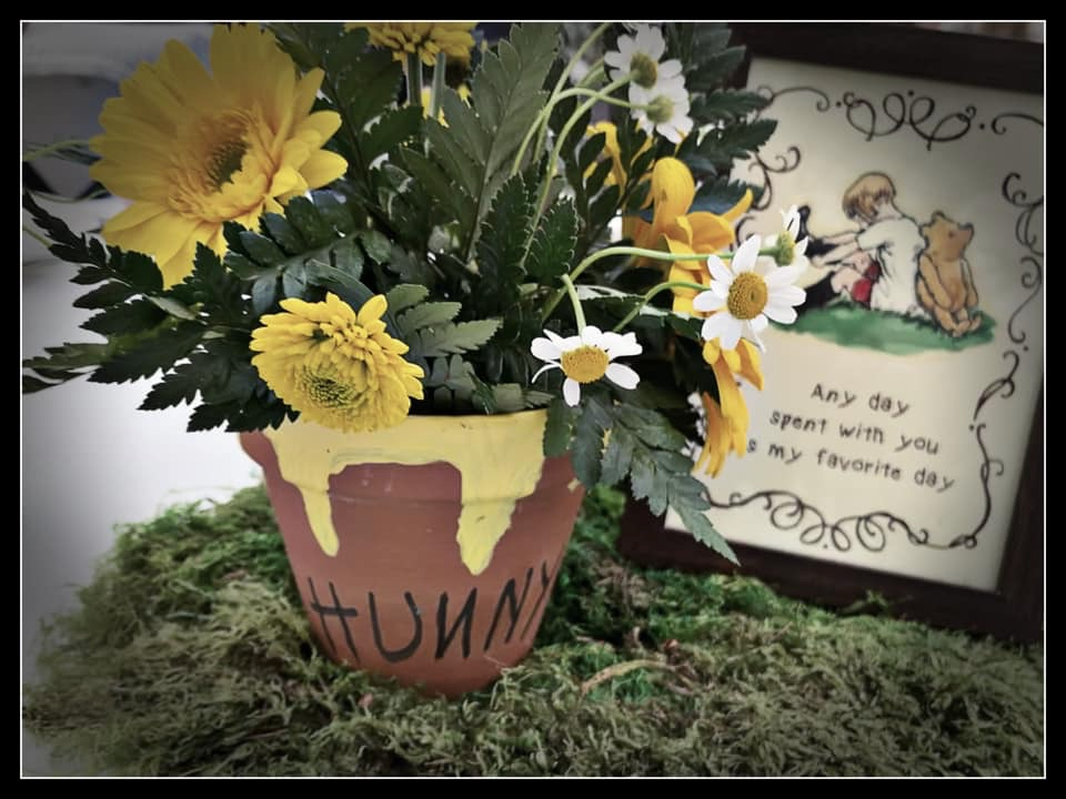 Rustic Winnie the Pooh baby sprinkle centerpiece with hunny pot flowers, moss, and vintage storybook artwork