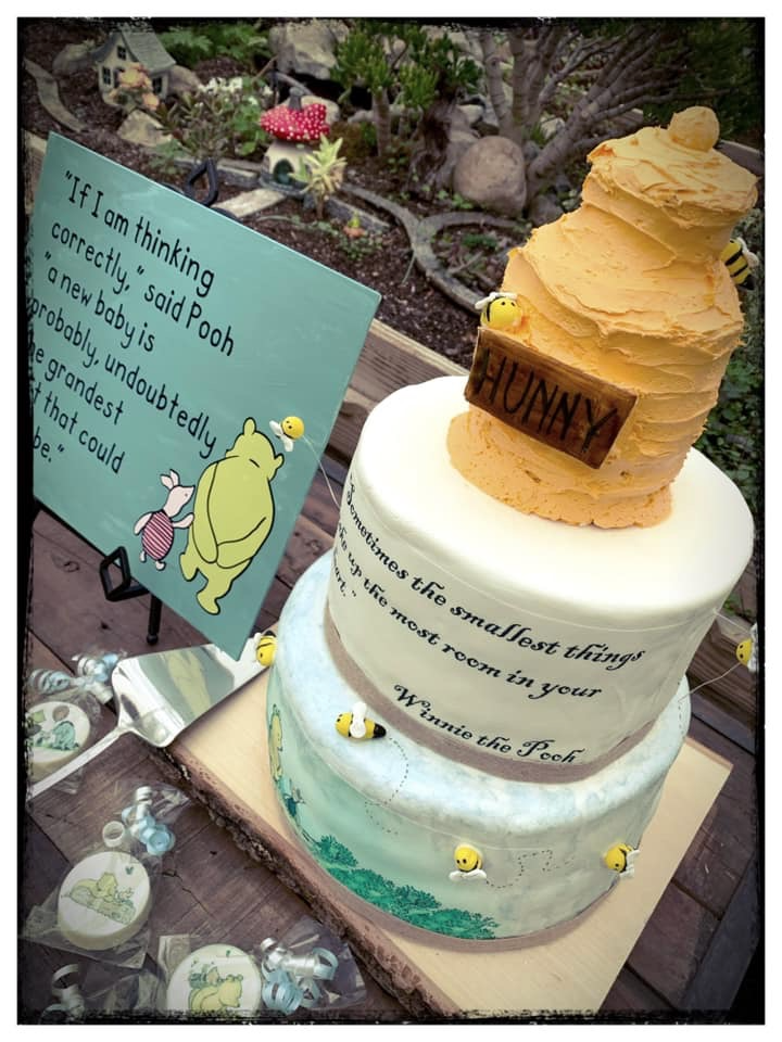 Vintage Winnie the Pooh baby sprinkle cake with honey pot topper, bee details, and classic storybook decor in a greenhouse setting