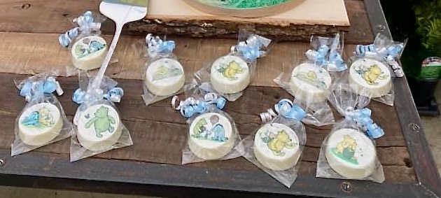 Winnie the Pooh themed chocolate-covered Oreos wrapped as baby sprinkle dessert favors on rustic wood table