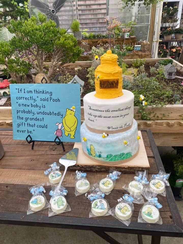 Vintage Winnie the Pooh baby sprinkle dessert table with storybook cake, themed chocolate-covered Oreos, and greenhouse garden decor